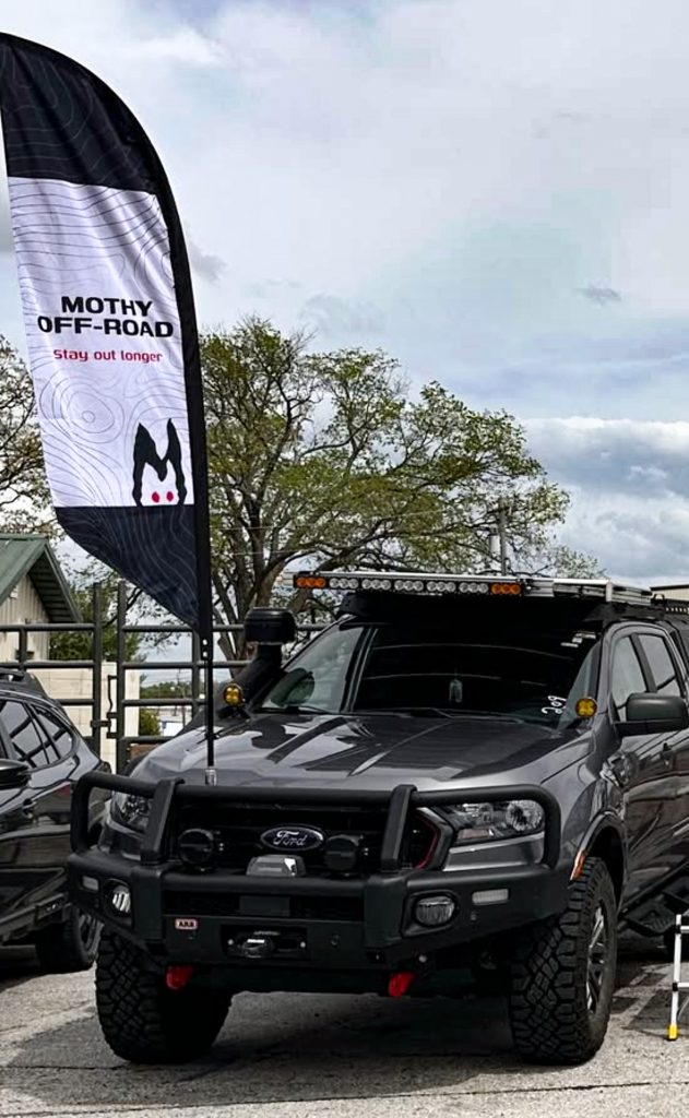 Photo of truck with solar rack with a Mothy Off-Road banner at an event